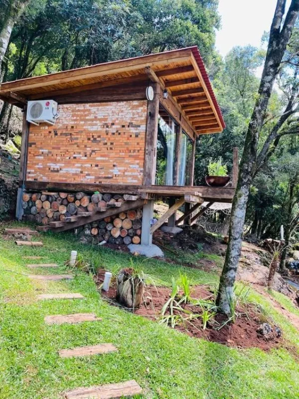 Cabana rústica de madeira sobre estacas em encosta verde